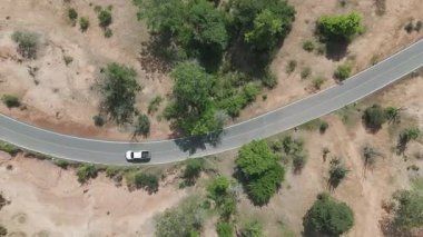 Kırsal bir yolda kırsal araziden geçen bir kamyonetin hava aracı görüntüsü. Doğada seyahat, ulaşım ve özgürlüğün manzaralı görüntüsü