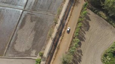 Kırsal bir yolda kırsal araziden geçen bir kamyonetin hava aracı görüntüsü. Doğada seyahat, ulaşım ve özgürlüğün manzaralı görüntüsü