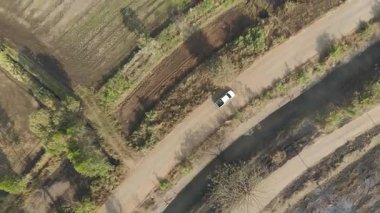 Kırsal bir yolda kırsal araziden geçen bir kamyonetin hava aracı görüntüsü. Doğada seyahat, ulaşım ve özgürlüğün manzaralı görüntüsü