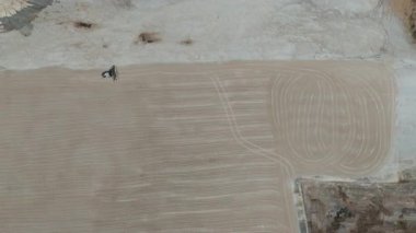 Drone videosu bir traktör cassava kurutma sahasına cassava yayıyor. Cassava un hazırlama süreci