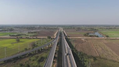 Kırsal kesimde tarlaları ve yolları olan otobandaki araçların insansız hava görüntüsü. Altyapı, lojistik veya ulaşım konsepti için ideal