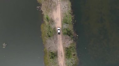 Kırsal bir yolda kırsal araziden geçen bir kamyonetin hava aracı görüntüsü. Doğada seyahat, ulaşım ve özgürlüğün manzaralı görüntüsü