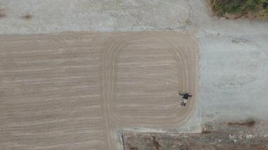 Drone videosu bir traktör cassava kurutma sahasına cassava yayıyor. Cassava un hazırlama süreci