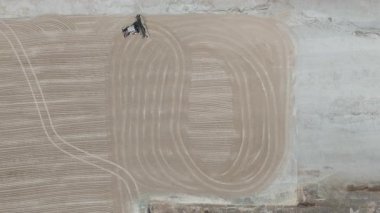 Drone videosu bir traktör cassava kurutma sahasına cassava yayıyor. Cassava un hazırlama süreci