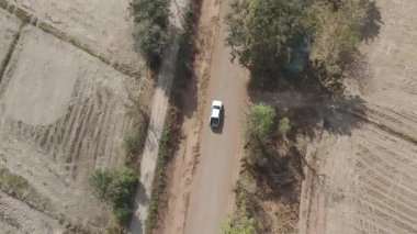 Kırsal bir yolda kırsal araziden geçen bir kamyonetin hava aracı görüntüsü. Doğada seyahat, ulaşım ve özgürlüğün manzaralı görüntüsü