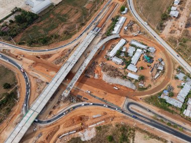 Vinç işçileri, traktörler ve kepçeler tarafından kavşağın üzerine beton köprü inşa edilmeden önce inşaat alanı