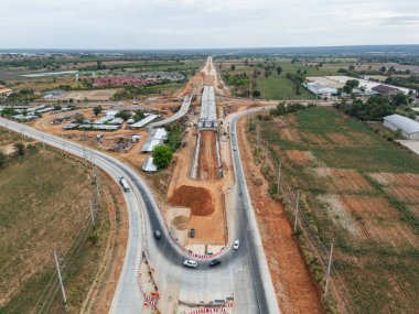 Vinç işçileri, traktörler ve kepçeler tarafından kavşağın üzerine beton köprü inşa edilmeden önce inşaat alanı
