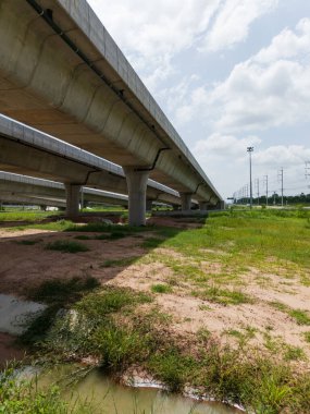 Otoyol kavşağı Tayland 'daki yeşil tarım arazilerinden geçiyor. Katmanlı yollar ve rampalar kırsal bir yerdeki modern ulaşım altyapısını vurguluyor