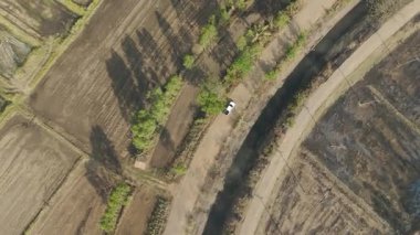 Kırsal bir yolda kırsal araziden geçen bir kamyonetin hava aracı görüntüsü. Doğada seyahat, ulaşım ve özgürlüğün manzaralı görüntüsü