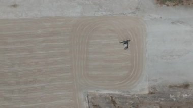 Drone videosu bir traktör cassava kurutma sahasına cassava yayıyor. Cassava un hazırlama süreci