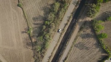 Kırsal bir yolda kırsal araziden geçen bir kamyonetin hava aracı görüntüsü. Doğada seyahat, ulaşım ve özgürlüğün manzaralı görüntüsü