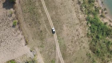 Kırsal bir yolda kırsal araziden geçen bir kamyonetin hava aracı görüntüsü. Doğada seyahat, ulaşım ve özgürlüğün manzaralı görüntüsü