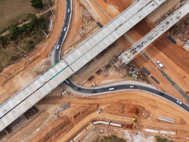 Vinç işçileri, traktörler ve kepçeler tarafından kavşağın üzerine beton köprü inşa edilmeden önce inşaat alanı