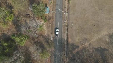 Kırsal bir yolda kırsal araziden geçen bir kamyonetin hava aracı görüntüsü. Doğada seyahat, ulaşım ve özgürlüğün manzaralı görüntüsü