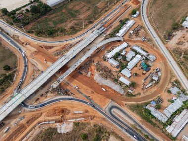 Vinç işçileri, traktörler ve kepçeler tarafından kavşağın üzerine beton köprü inşa edilmeden önce inşaat alanı