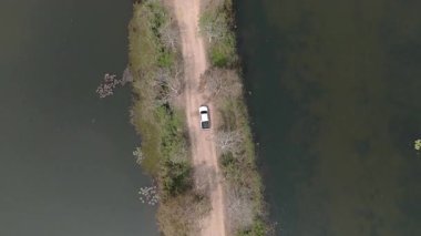 Kırsal bir yolda kırsal araziden geçen bir kamyonetin hava aracı görüntüsü. Doğada seyahat, ulaşım ve özgürlüğün manzaralı görüntüsü