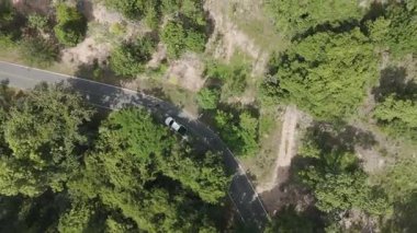 Kırsal bir yolda kırsal araziden geçen bir kamyonetin hava aracı görüntüsü. Doğada seyahat, ulaşım ve özgürlüğün manzaralı görüntüsü