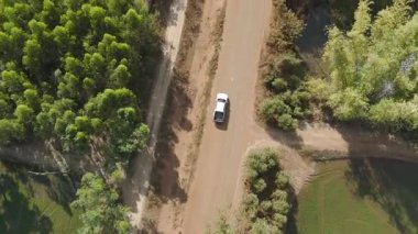 Kırsal bir yolda kırsal araziden geçen bir kamyonetin hava aracı görüntüsü. Doğada seyahat, ulaşım ve özgürlüğün manzaralı görüntüsü