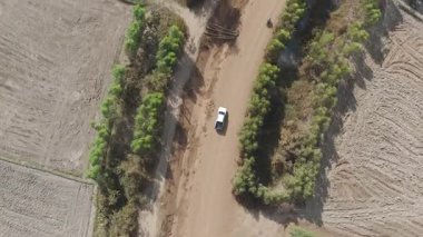 Kırsal bir yolda kırsal araziden geçen bir kamyonetin hava aracı görüntüsü. Doğada seyahat, ulaşım ve özgürlüğün manzaralı görüntüsü