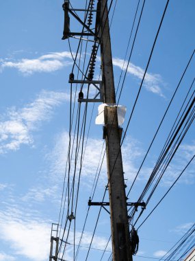 Elektrik hatları mavi gökyüzü boyunca uzanıyor, yüksek çelik kulelerle destekleniyor, bulutlarla harmanlanırken elektrik ve enerji iletiliyor.