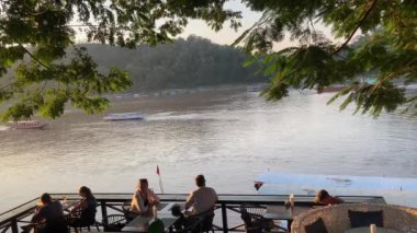 Luang Prabang 'daki turizm tekneleri Mekong nehri boyunca gün batımında manzaralı geziler sunuyor. 4k video kaydı