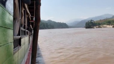 Mekong Nehri 'ndeki tekneler, arka planda yükselen yüksek dağlar, çarpıcı ve doğal bir manzara yaratıyor. 4k video kaydı