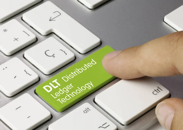 Stock image DLT Distributed Ledger Technology Written on Green Key of Metallic Keyboard. Finger pressing key.