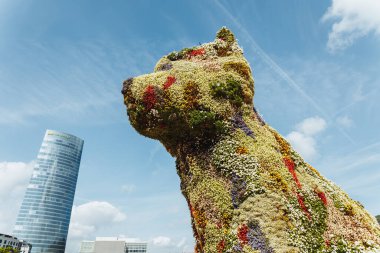 Bilbao, İspanya - Eylül 2022: Puppy, güneşli bir günde Jeff Koons ve Iberdrola kulesi tarafından tasarlanan çiçekli köpek heykeli