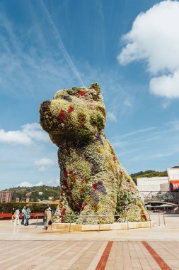 Bilbao, İspanya - Eylül 2022: Güneşli bir günde İspanya 'nın Bilbao kentindeki Guggenheim Müzesi' nin önünde Jeff Koons tarafından tasarlanan çiçekli köpek heykeli.