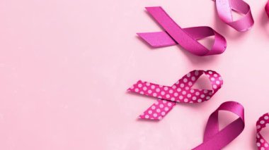 Göğüs Kanseri Farkındalığı Ayı ve Dünya Kanser Günü için fotokopi alanı olan pembe bir zemin üzerinde pembe kurdeleler.