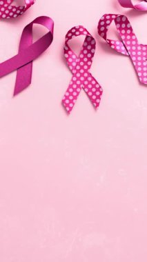 Göğüs Kanseri Farkındalığı Ayı ve Dünya Kanser Günü için fotokopi alanı olan pembe bir zemin üzerinde pembe kurdeleler.