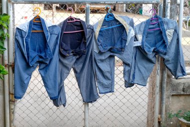 Bahçede çitin üstünde kurutulmuş kot, yıkandıktan sonra güneş ışığında asılı..