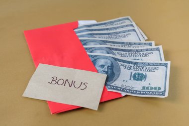 BONUS yazılı kırmızı zarf içinde nakit dolar para, personel ve çalışanlar için konsept bonus ödülü.