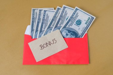 BONUS yazılı kırmızı zarf içinde nakit dolar para, personel ve çalışanlar için konsept bonus ödülü.