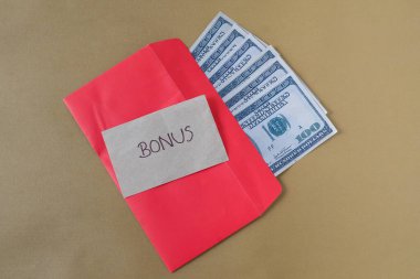 BONUS yazılı kırmızı zarf içinde nakit dolar para, personel ve çalışanlar için konsept bonus ödülü.