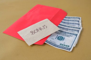 BONUS yazılı kırmızı zarf içinde nakit dolar para, personel ve çalışanlar için konsept bonus ödülü.