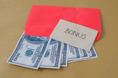 BONUS yazılı kırmızı zarf içinde nakit dolar para, personel ve çalışanlar için konsept bonus ödülü.