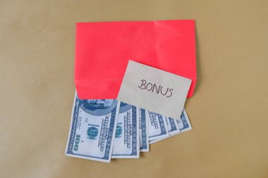 BONUS yazılı kırmızı zarf içinde nakit dolar para, personel ve çalışanlar için konsept bonus ödülü.