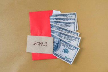 BONUS yazılı kırmızı zarf içinde nakit dolar para, personel ve çalışanlar için konsept bonus ödülü.