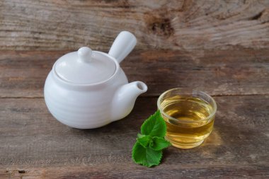 Beyaz çay demliği ve tahtadan yapılmış bir bardak sıcak içecek..