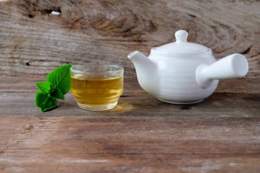 Beyaz çay demliği ve tahtadan yapılmış bir bardak sıcak içecek..