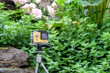 Bahçedeki kayanın üzerinde su geçirmez çantalı aksiyon kamerası..