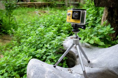 Bahçedeki kayanın üzerinde su geçirmez çantalı aksiyon kamerası..