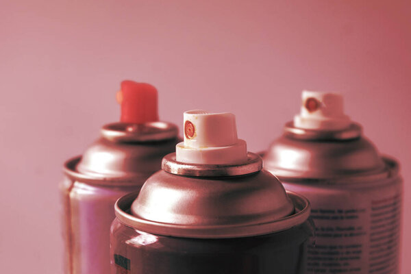 Used cans of spray paints on color background.