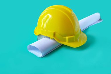 Mimar ruloları ve kaskı masanın üzerine çizer..