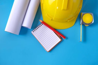 Arka planda kask ve mezura, inşaat projesi üzerinde çalışıyor.