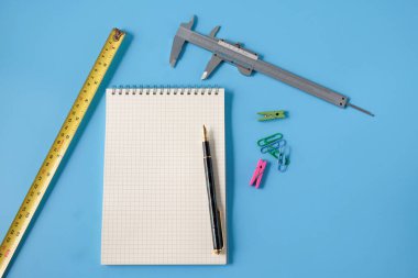 Arka planda not defteri ve mezura ölçüsü.