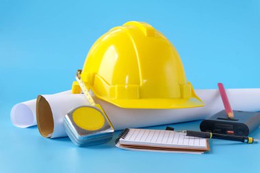 Arka planda kask ve mezura, inşaat projesi üzerinde çalışıyor.