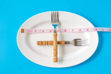 Çatal ve bıçak, beyaz tabakların etrafında mezura. Sağlık konsepti..