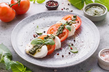 Fesleğenli, pesto soslu ve zeytinyağlı mozzarella ile domates. Yüksek kalite fotoğraf